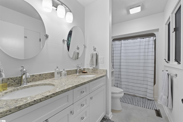 bathroom with tile patterned floors, walk in shower, a textured ceiling, vanity, and toilet