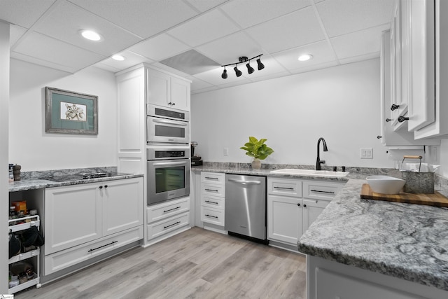 kitchen featuring appliances with stainless steel finishes, light hardwood / wood-style floors, white cabinetry, and sink