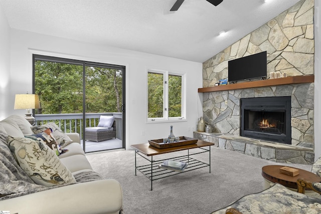 living room featuring a textured ceiling, a stone fireplace, carpet, and lofted ceiling