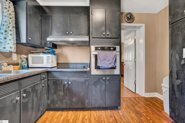 kitchen featuring sink, black electric stovetop, oven, and light wood-type flooring