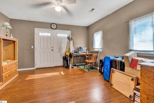 foyer entrance with hardwood / wood-style floors, ceiling fan, and a textured ceiling