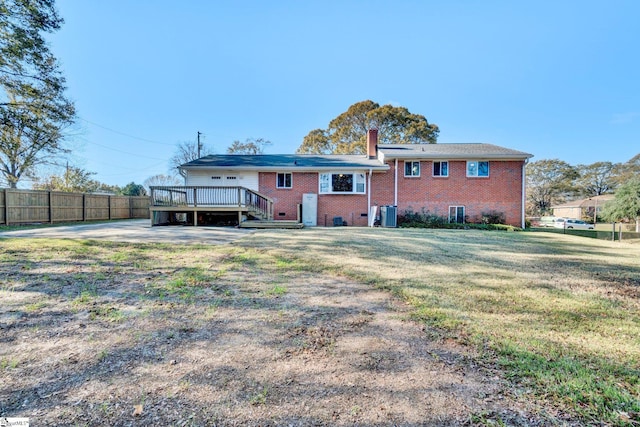 rear view of property featuring central AC unit, a yard, and a wooden deck