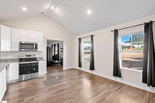 kitchen featuring white cabinets, light wood-type flooring, vaulted ceiling, and appliances with stainless steel finishes