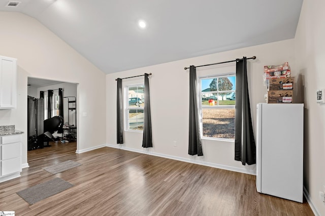 unfurnished room featuring light wood-type flooring and vaulted ceiling