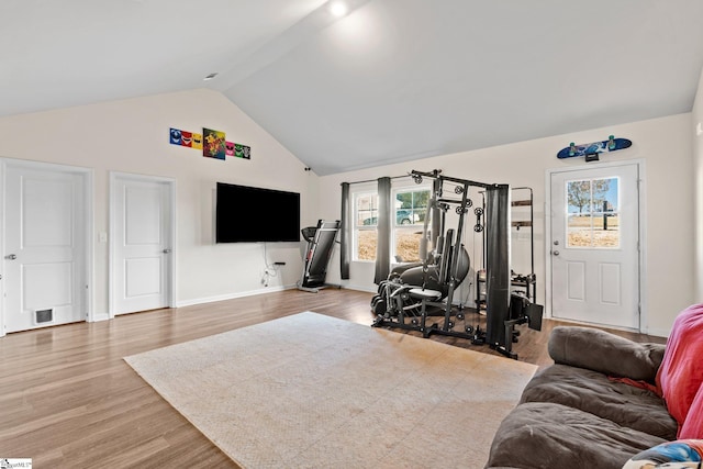 exercise area with wood-type flooring and high vaulted ceiling