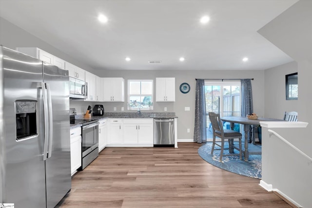 kitchen with a wealth of natural light, white cabinetry, appliances with stainless steel finishes, and light hardwood / wood-style flooring