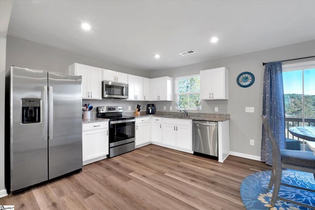 kitchen featuring light stone countertops, appliances with stainless steel finishes, sink, light hardwood / wood-style flooring, and white cabinetry