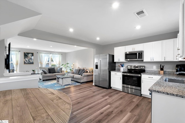 kitchen with light stone countertops, white cabinetry, sink, dark wood-type flooring, and appliances with stainless steel finishes