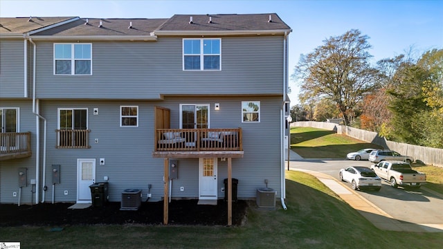 rear view of property featuring central AC, a yard, and a balcony