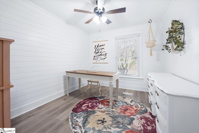 office space with dark hardwood / wood-style floors, ceiling fan, ornamental molding, and wooden walls