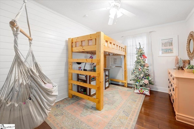 bedroom with ornamental molding, wooden walls, a textured ceiling, and dark wood-type flooring