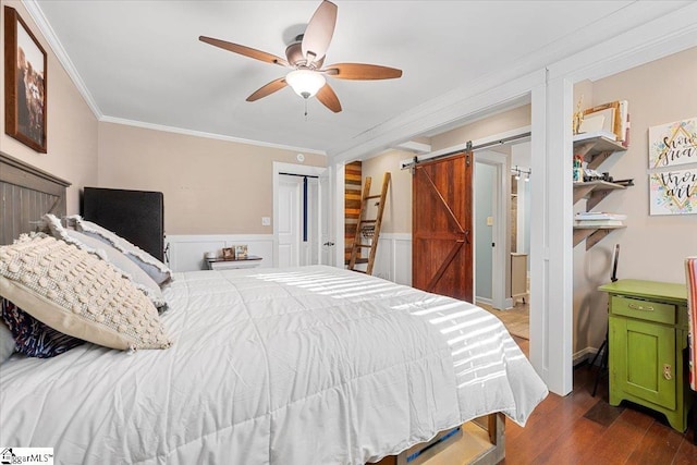 bedroom featuring hardwood / wood-style flooring, ceiling fan, a barn door, ornamental molding, and a closet