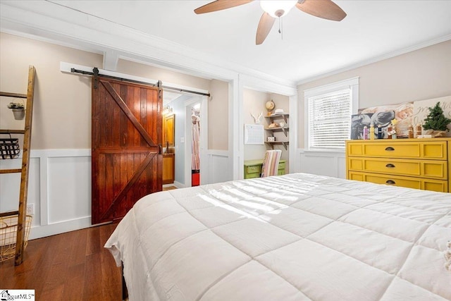 bedroom featuring ceiling fan, a barn door, crown molding, and dark hardwood / wood-style floors