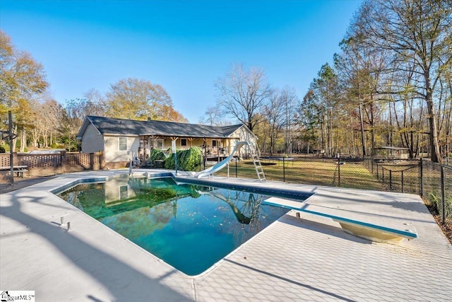 view of swimming pool featuring a diving board and a water slide