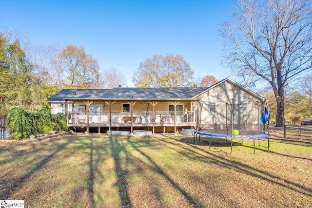 rear view of house featuring a yard, a deck, and a trampoline