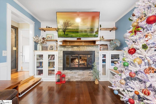 unfurnished living room featuring hardwood / wood-style flooring, a stone fireplace, and ornamental molding