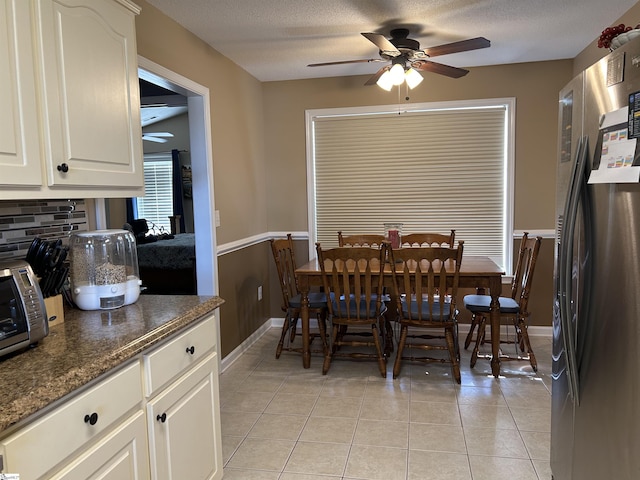 dining space featuring ceiling fan, light tile patterned floors, and a textured ceiling