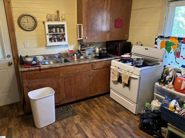 kitchen featuring dark hardwood / wood-style flooring, wood walls, sink, and white gas range oven