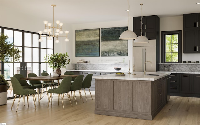 kitchen with sink, built in refrigerator, an island with sink, decorative backsplash, and light wood-type flooring