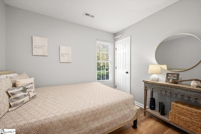 bedroom with wood-type flooring and a textured ceiling