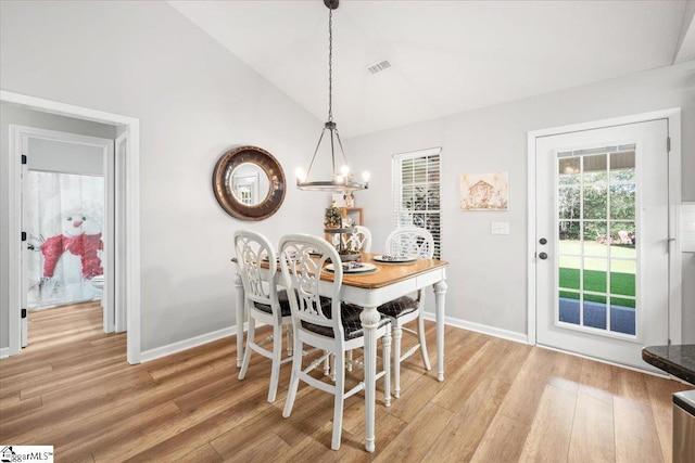 dining area featuring light wood-type flooring, lofted ceiling, and an inviting chandelier