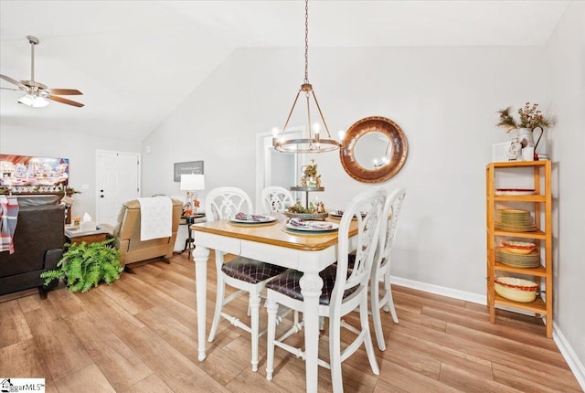 dining space featuring ceiling fan with notable chandelier, light hardwood / wood-style floors, and vaulted ceiling