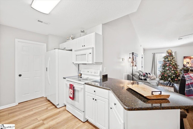 kitchen with white cabinetry, backsplash, dark stone countertops, white appliances, and light wood-type flooring