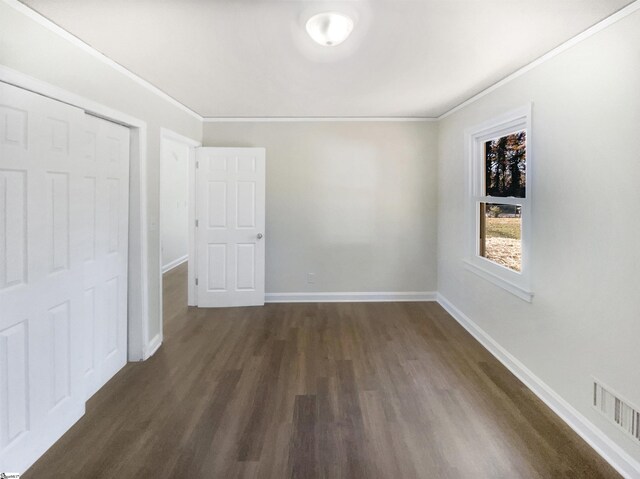 unfurnished bedroom with ornamental molding, dark wood-type flooring, and a closet