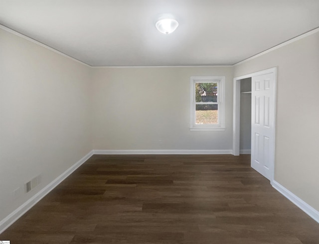 unfurnished bedroom featuring dark hardwood / wood-style flooring, ornamental molding, and a closet