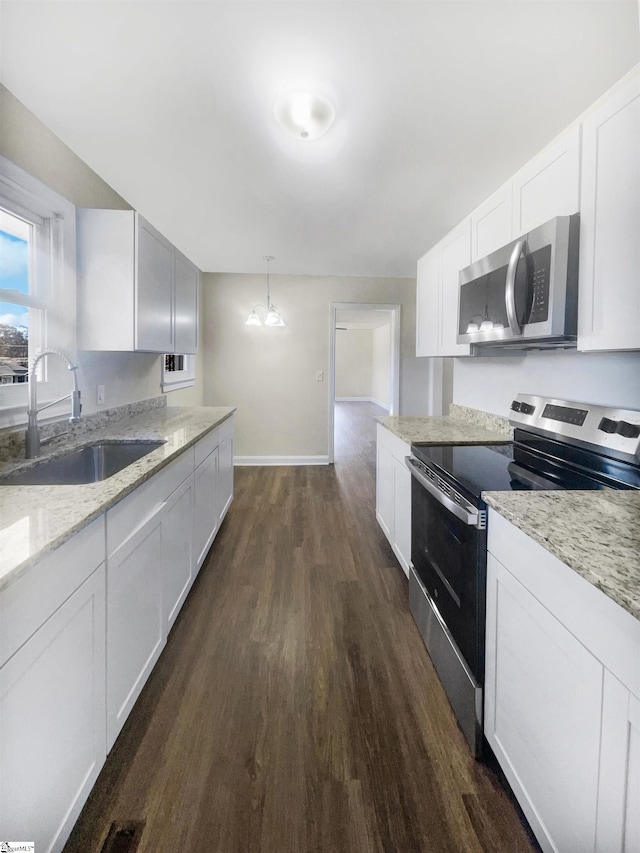 kitchen featuring stainless steel appliances, dark wood-type flooring, sink, white cabinetry, and hanging light fixtures