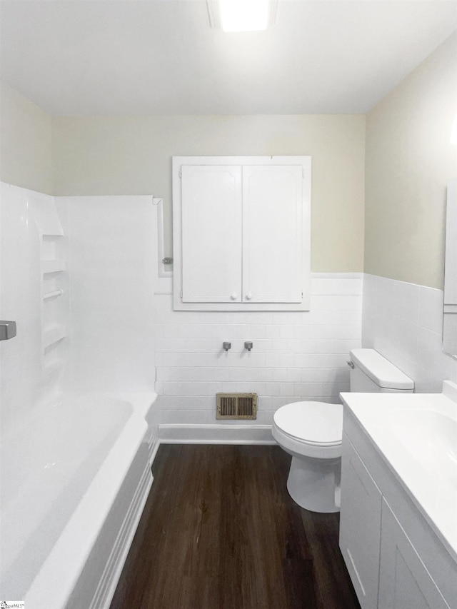 bathroom with vanity, toilet, wood-type flooring, and tile walls