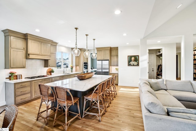 kitchen with a kitchen island, light wood-type flooring, stainless steel appliances, and hanging light fixtures