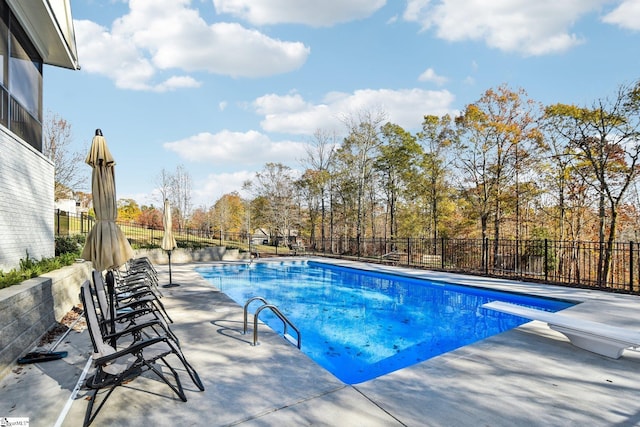 view of swimming pool featuring a diving board and a patio area