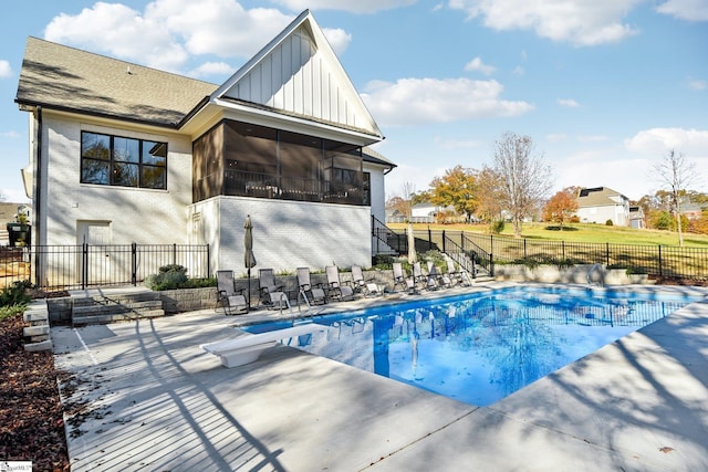 view of swimming pool with a patio area, a sunroom, and a diving board