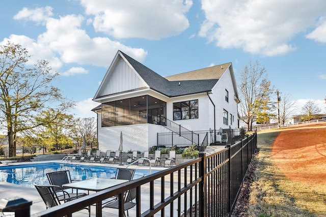 rear view of property with a sunroom and a fenced in pool