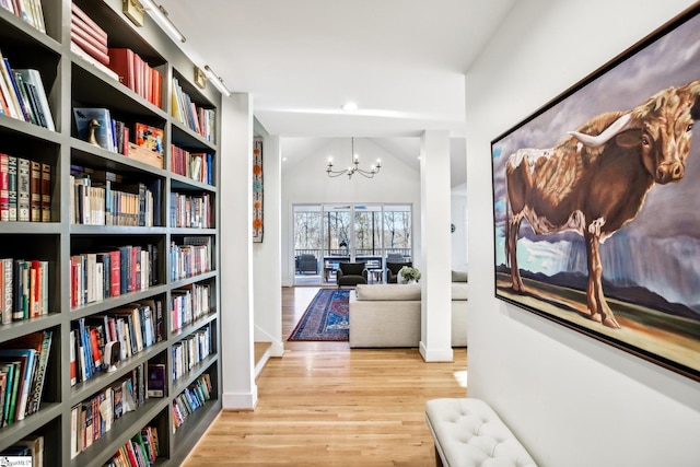 interior space featuring vaulted ceiling, a notable chandelier, and light wood-type flooring