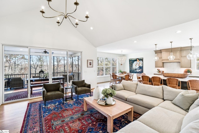 living room featuring ceiling fan with notable chandelier, wood-type flooring, and high vaulted ceiling