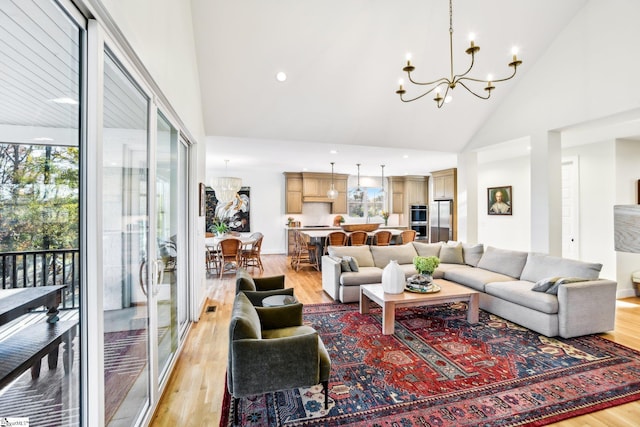 living room featuring high vaulted ceiling, a notable chandelier, and light wood-type flooring