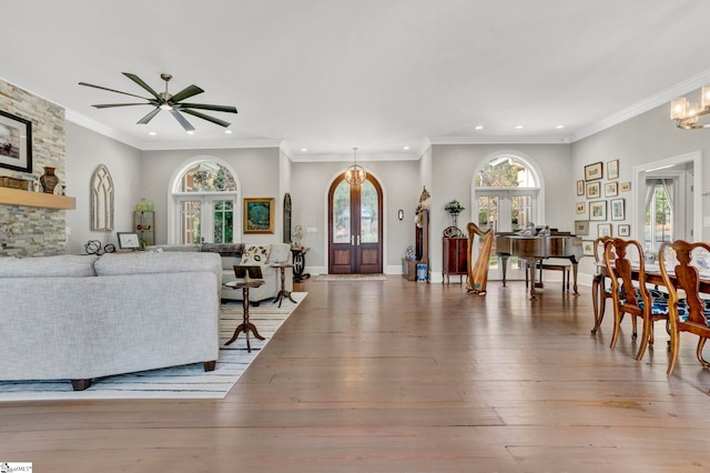 living room featuring a wealth of natural light, french doors, crown molding, and light hardwood / wood-style flooring