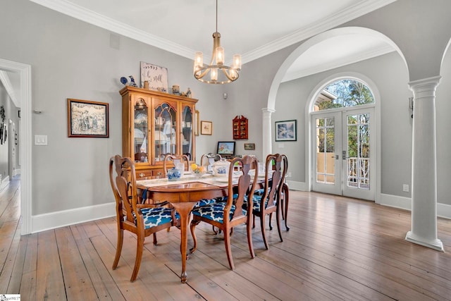 dining space featuring a chandelier, french doors, light wood-type flooring, and ornamental molding