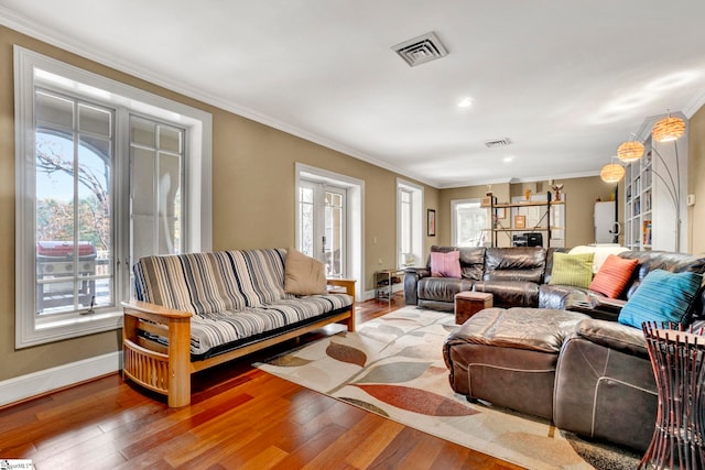 living room with wood-type flooring, a wealth of natural light, and crown molding