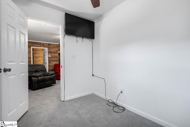 carpeted spare room with wood walls and ceiling fan