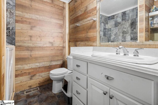 bathroom with wood walls, vanity, and toilet