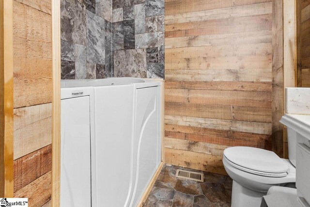 bathroom featuring wood walls and toilet