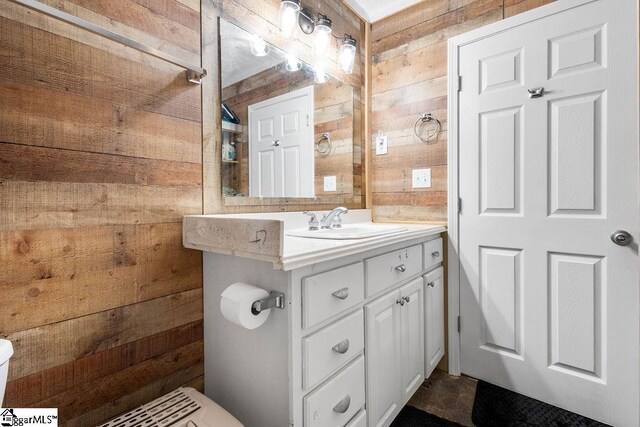 bathroom with vanity, toilet, and wooden walls