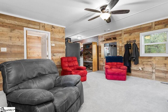 living room with carpet floors, ceiling fan, and wood walls