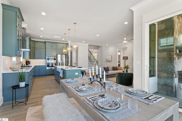 dining space with ceiling fan, sink, and light hardwood / wood-style floors