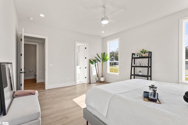 bedroom featuring ceiling fan, ensuite bathroom, and light hardwood / wood-style flooring