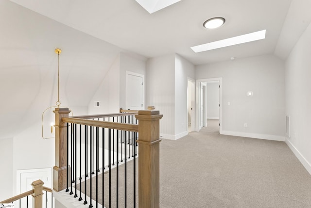 corridor featuring vaulted ceiling with skylight and light carpet