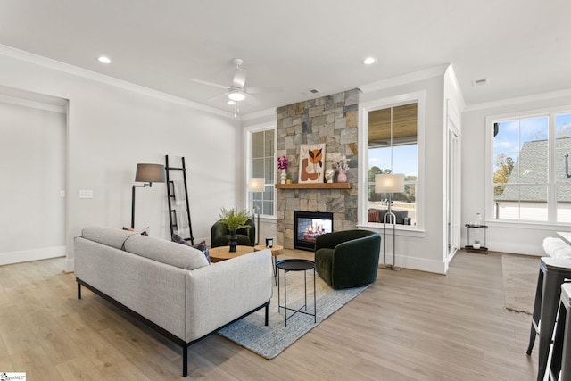 living room featuring a fireplace, light hardwood / wood-style floors, ceiling fan, and crown molding